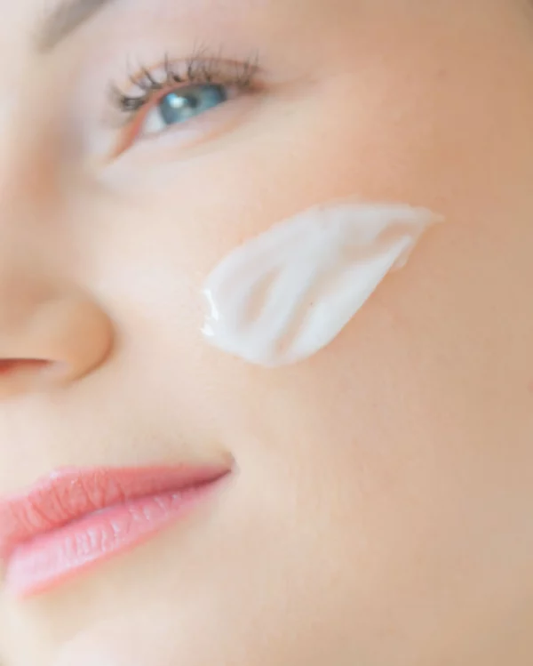 Woman applying La Crème Aliscential to her cheek – lightweight face cream with rose hydrosol to hydrate and soothe the skin.