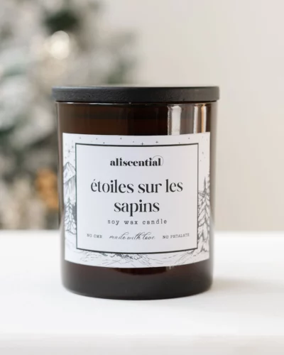 Bougie parfumée étoiles sur les sapins. Aliscential en verre brun, packshot sur fond épuré.